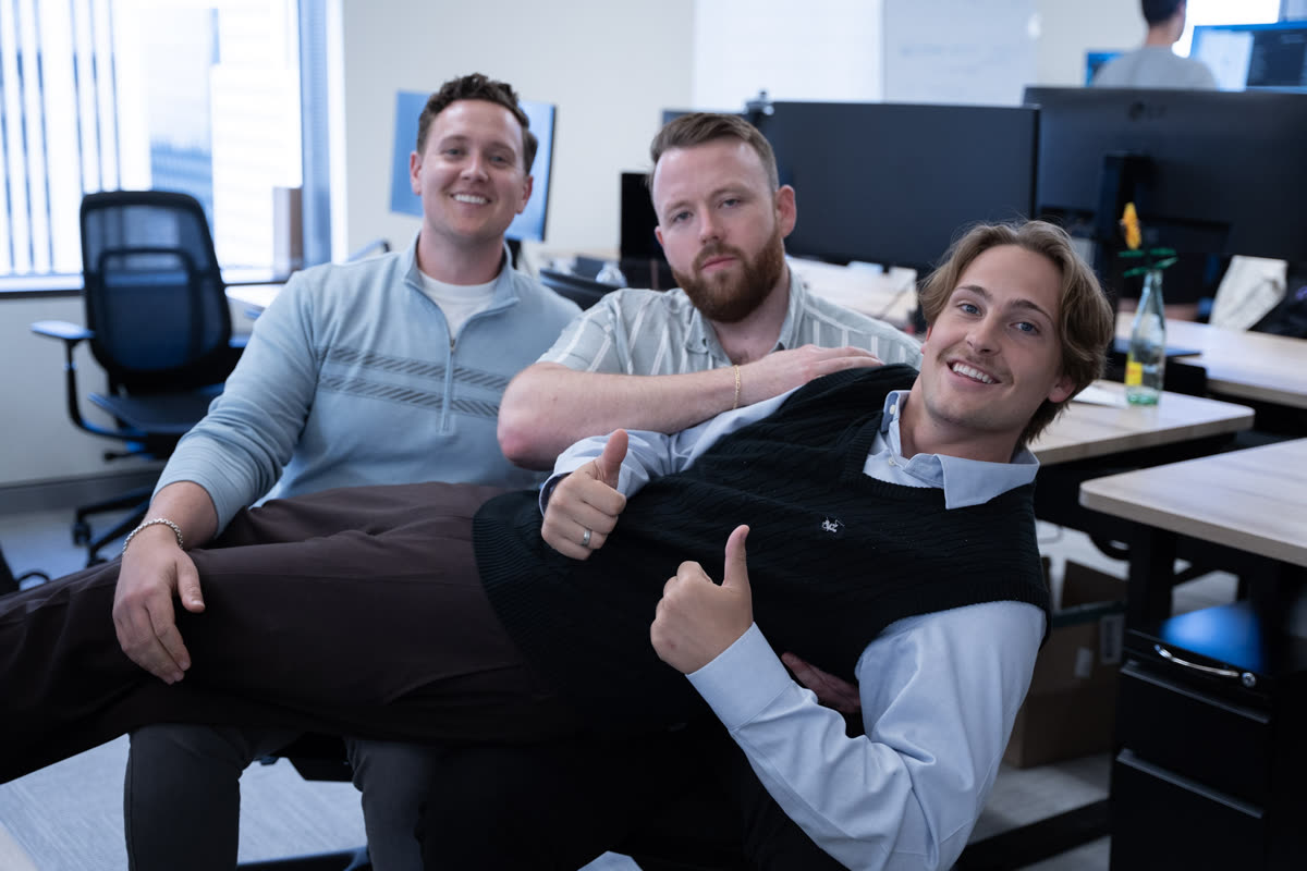 Three teammates goofing around at their desks