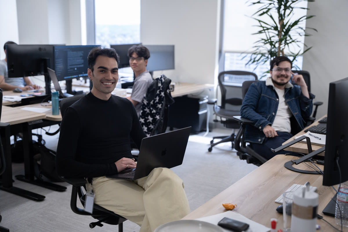Three teammates smiling at their desks